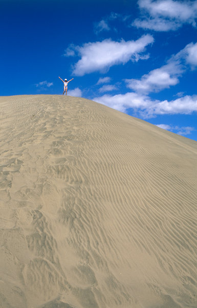 Flicka p toppen av en sanddyn.