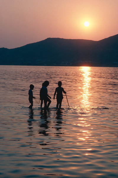 Barn fiskar i solnedgngen.